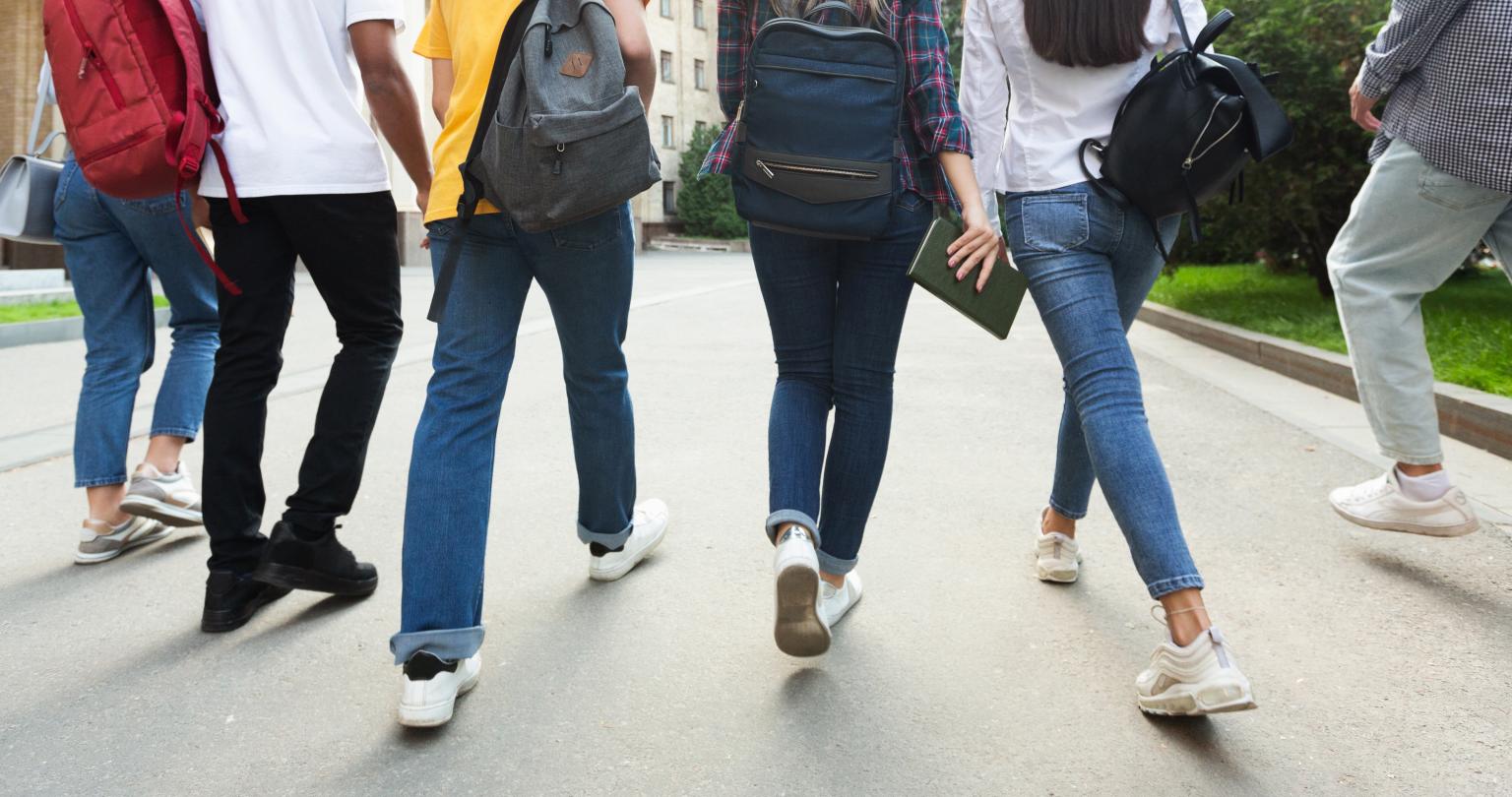 Unrecognizable teenage students in high school campus walking at break, crop