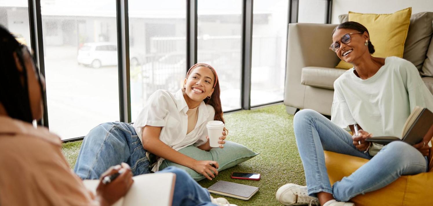 Writing, studying and collaboration student friends in university lounge for a group project, teamwork and planning schedule. Young women relax with coffee and brainstorming ideas and time management.