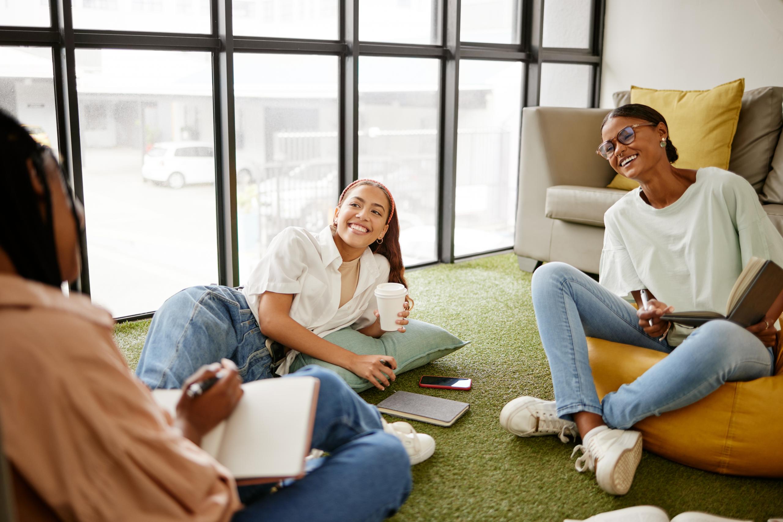 Writing, studying and collaboration student friends in university lounge for a group project, teamwork and planning schedule. Young women relax with coffee and brainstorming ideas and time management.