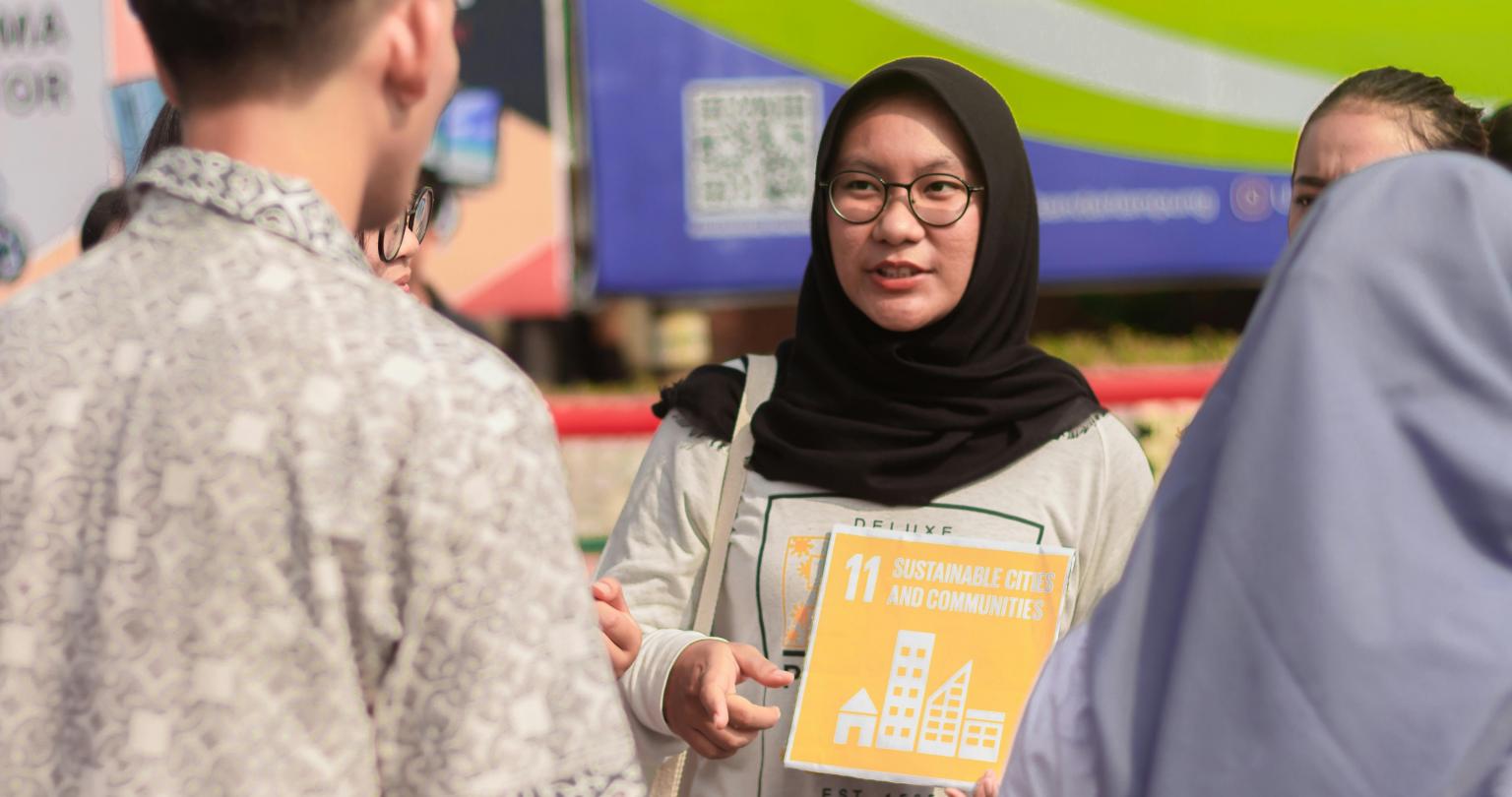 Young girl wearing a hijab and holding a sign with the words 